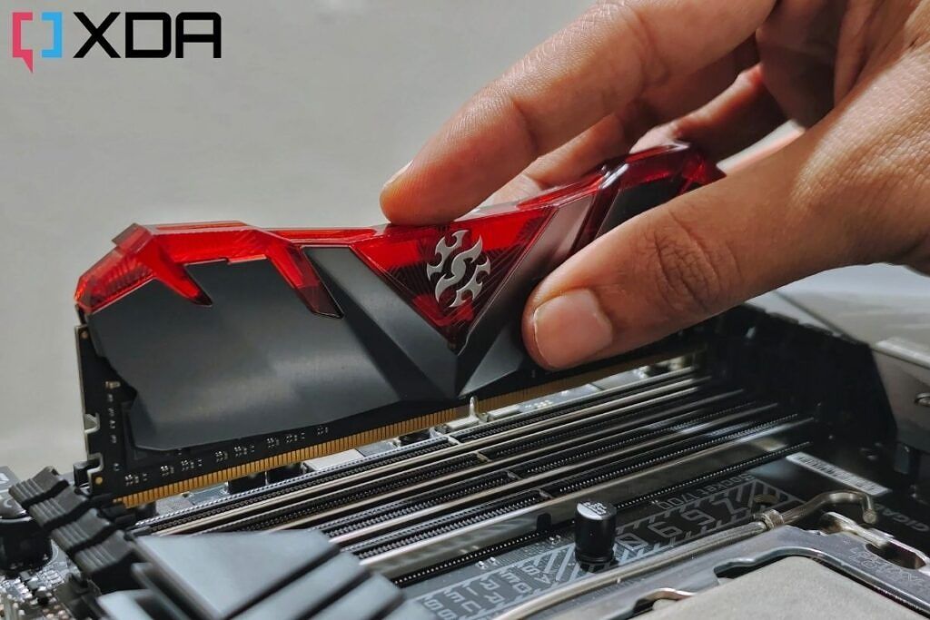 An XPG RAM module with a red-colored heat spreader being installed on a motherboard