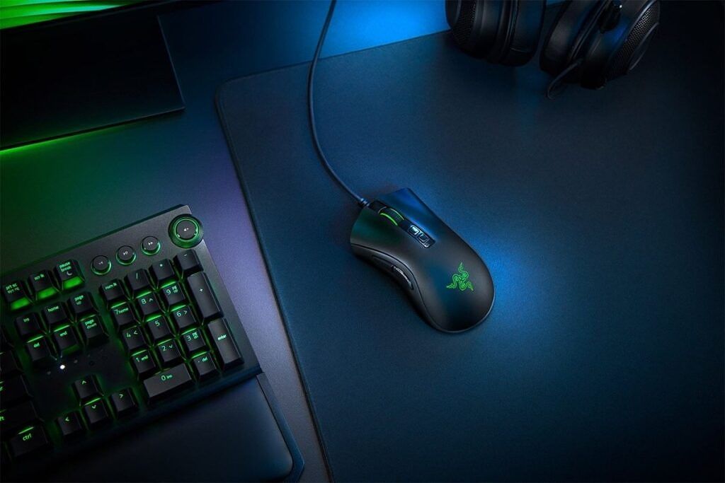 A black colored Razer gaming mouse kept on a table next to other gaming peripherals