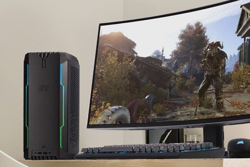 A black colored Corsair One compact gaming PC next to a monitor on a desk